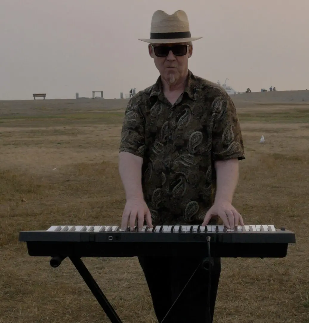A man in sunglasses and hat playing the piano.